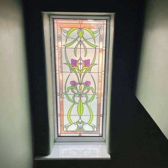 Cynthia stained glass window film in a Victorian style with purple flowers installed onto a window with walls of similar green colour to match.