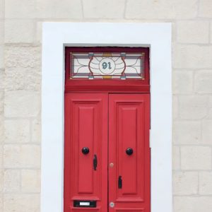 Victorian gothic stained glass window film with central door number installed above a red door