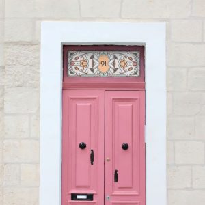 A floral stained glass window film with central door number installed above a pink door
