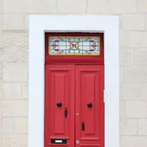 Stained glass window film installed above a red door with a central door number on.