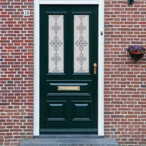 An ornate cross design in a Victorian frosted door window film installed on an old door